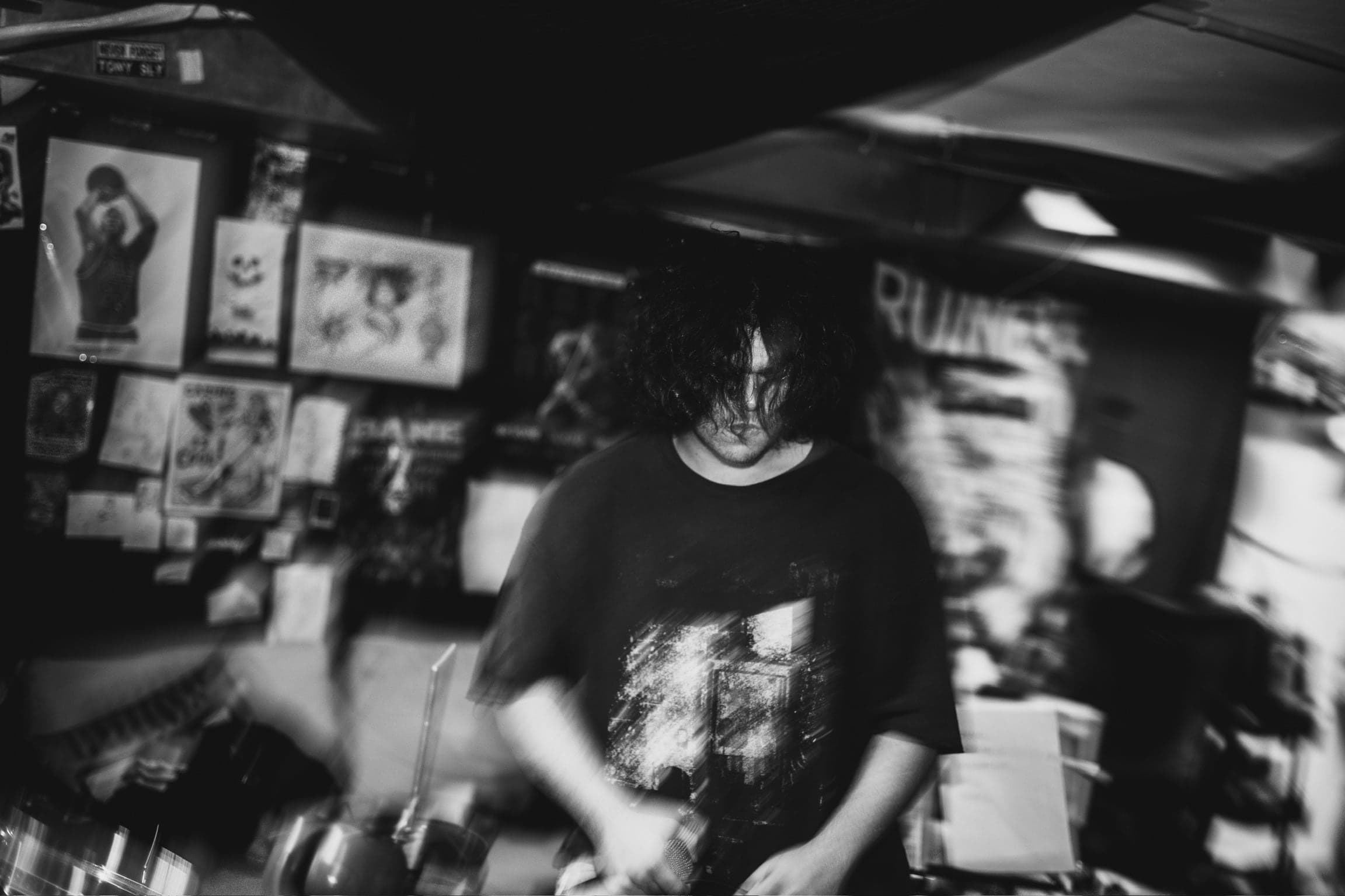 Black and white — the vocalist's head drops, hair falling over his face, the frame dissolving into motion blur.