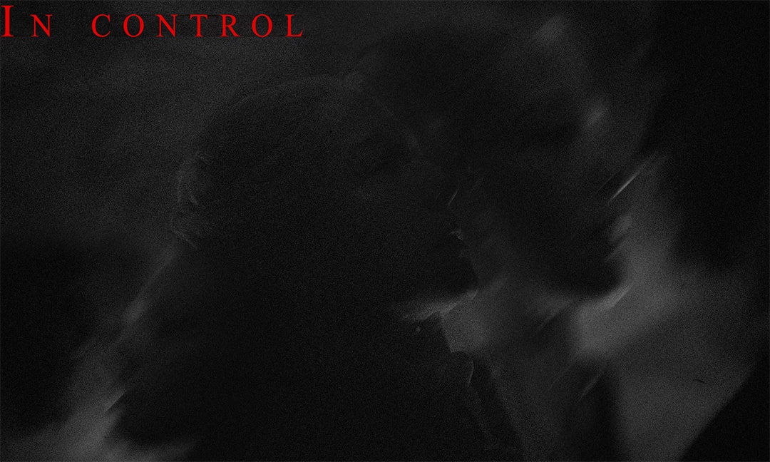 A dark, grainy close silhouette of two figures, titled 'IN CONTROL.'